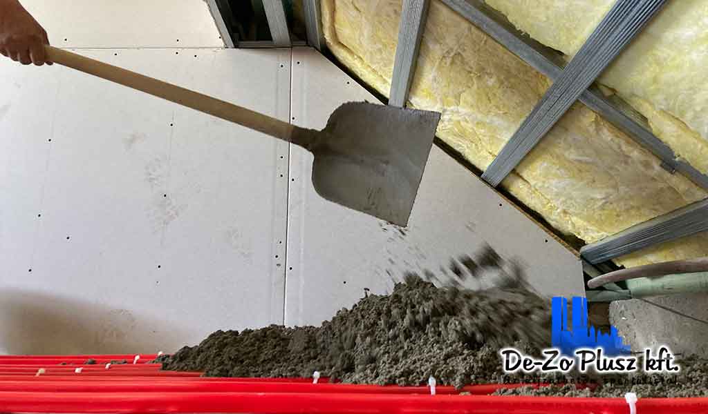 Lapáttal adagolt estrich beton padlófűtés fölé, kézi betonozás szigetelt belső térben, aljzatkiegyenlítő réteg készítése.